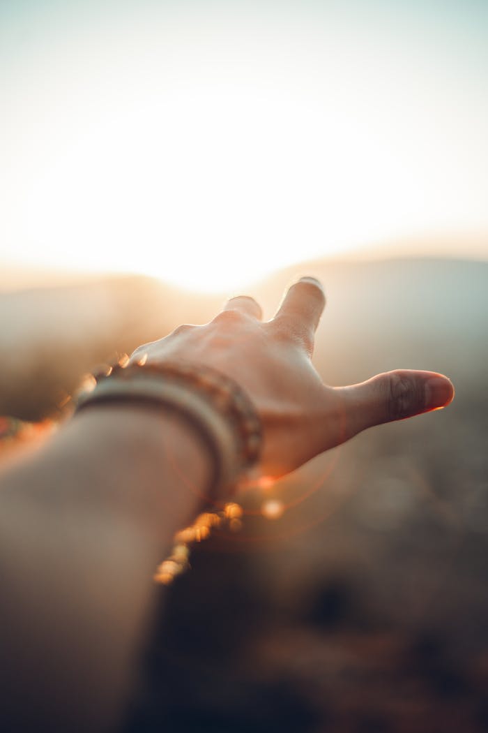 get-in-touch A hand adorned with bracelets reaching towards the sunlight in Beirut, capturing a vibrant moment.