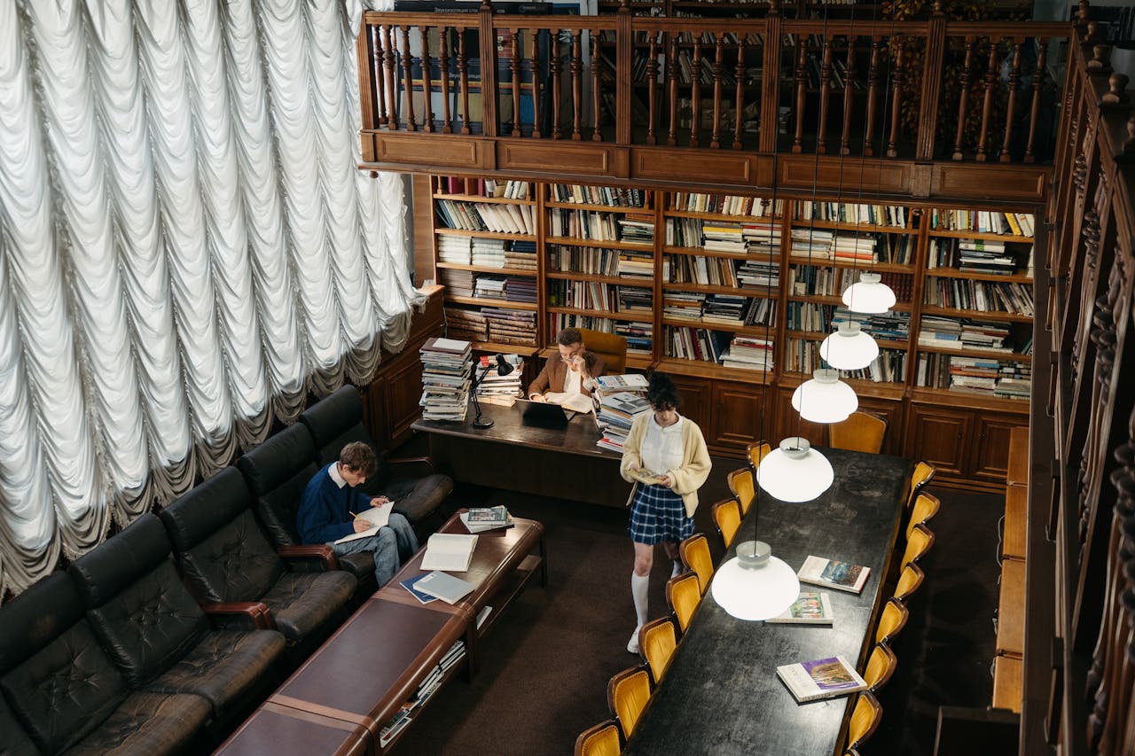 Students studying in a cozy public library with classic bookshelves and warm lighting.